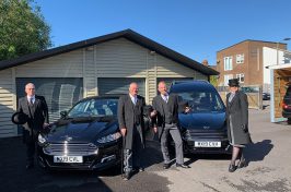 funeral directors in front of funeral cars